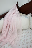 Pink lacy blanket displayed in a crib