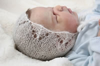 Knitted white baby bonnet
